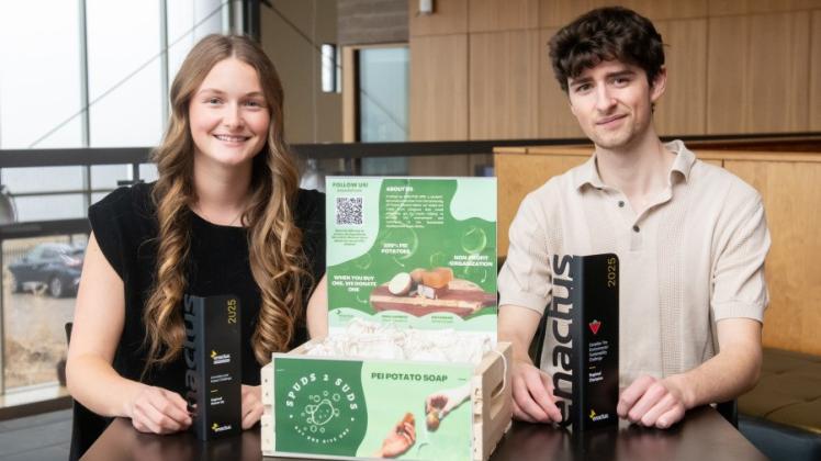 Two Enactus UPEI students holding a box of potatoes representing the Spuds2Suds student soap initiative