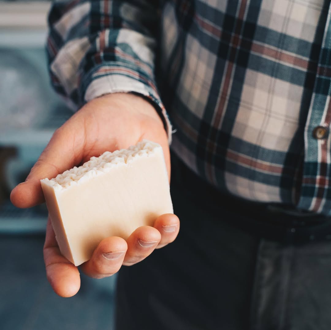Hand holding a bar of soap with a blurred background