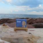 Bar of soap on a wooden stand with 'Anne' branding against a beach background