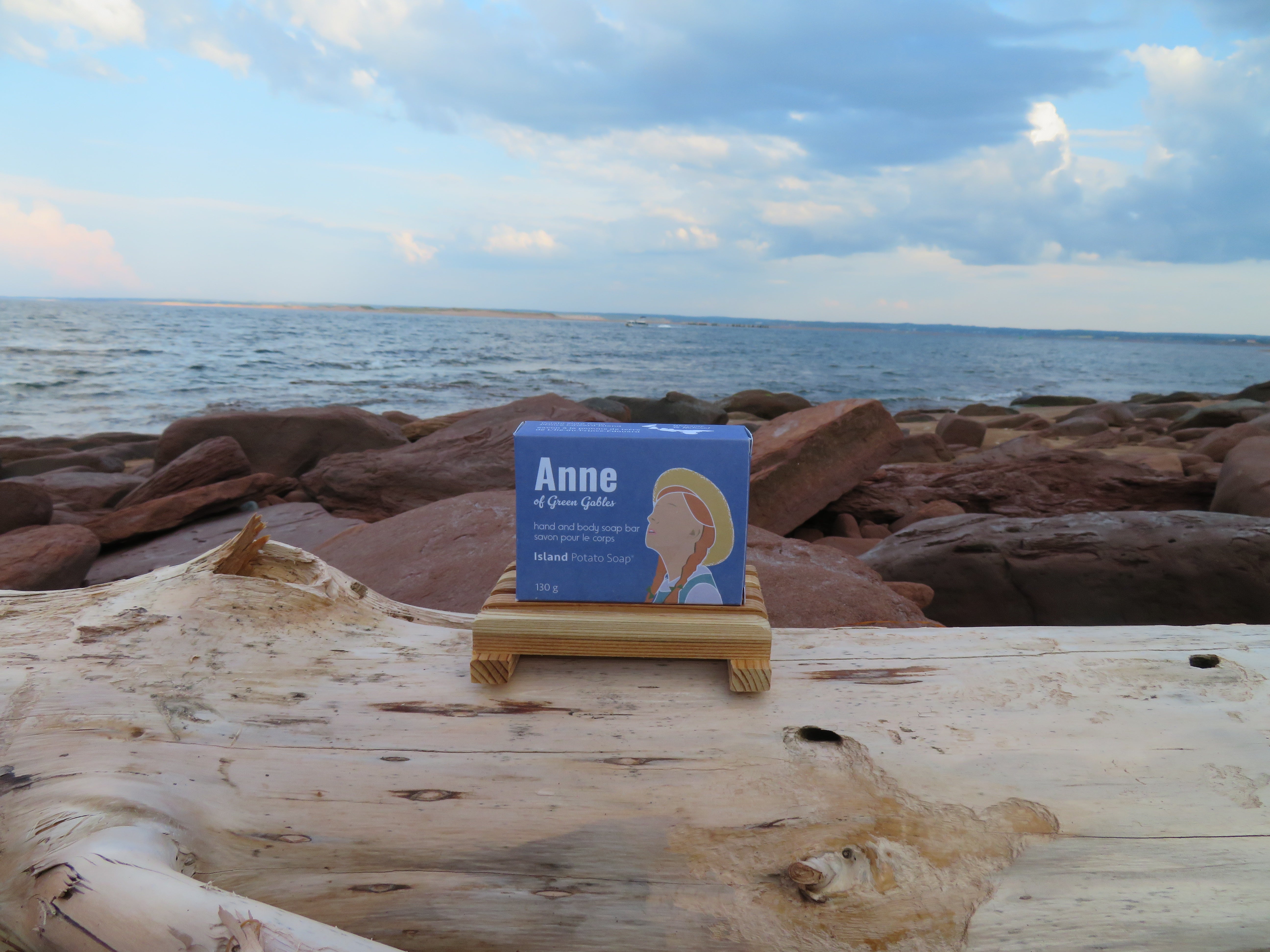 Bar of soap on a wooden stand with 'Anne' branding against a beach background