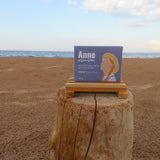 Box labeled 'Anne' on a wooden stump with a beach and ocean background