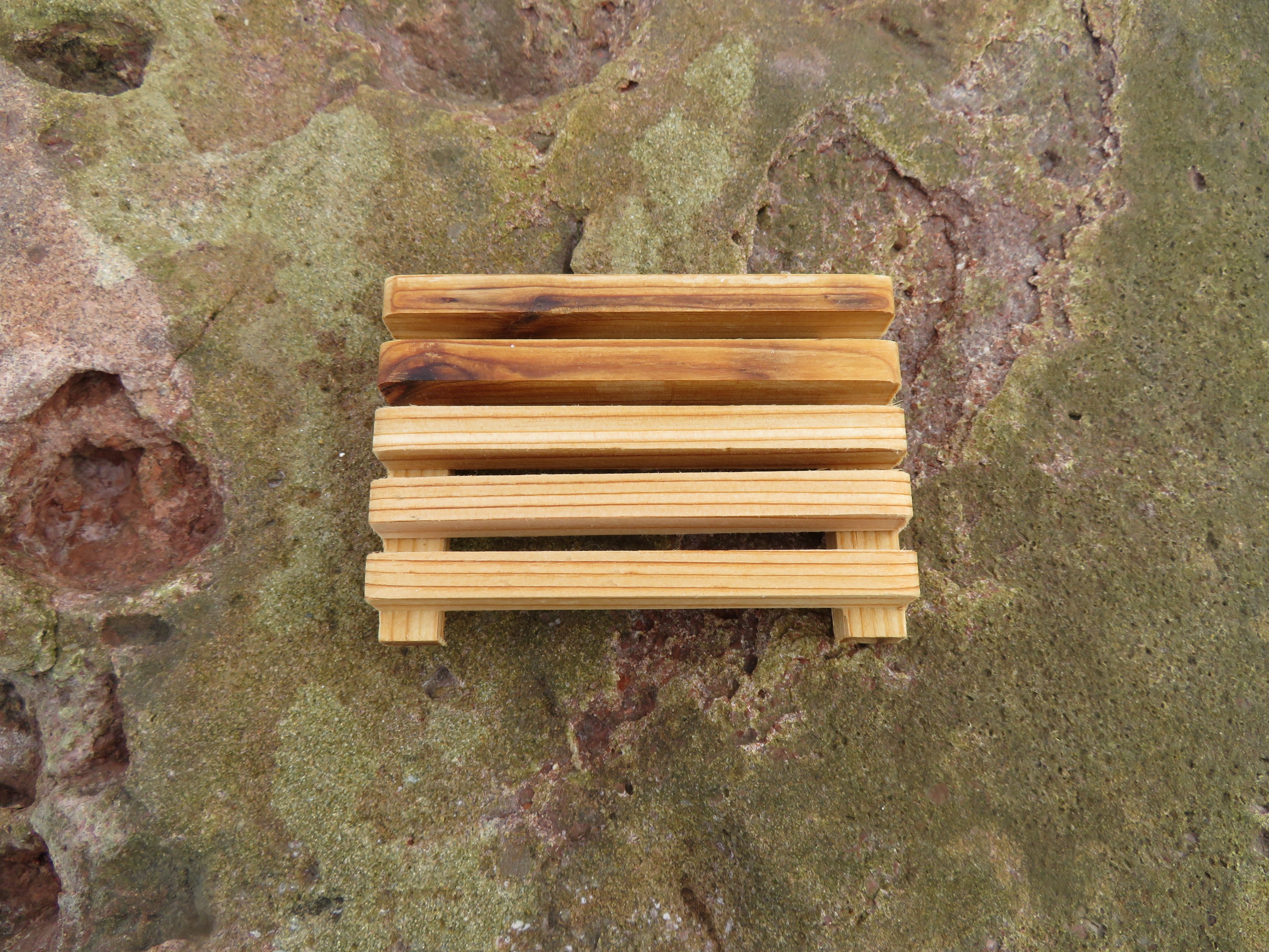 Wooden soap dish attached to a textured stone wall