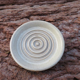 Ceramic disc with concentric circles on a textured brown surface