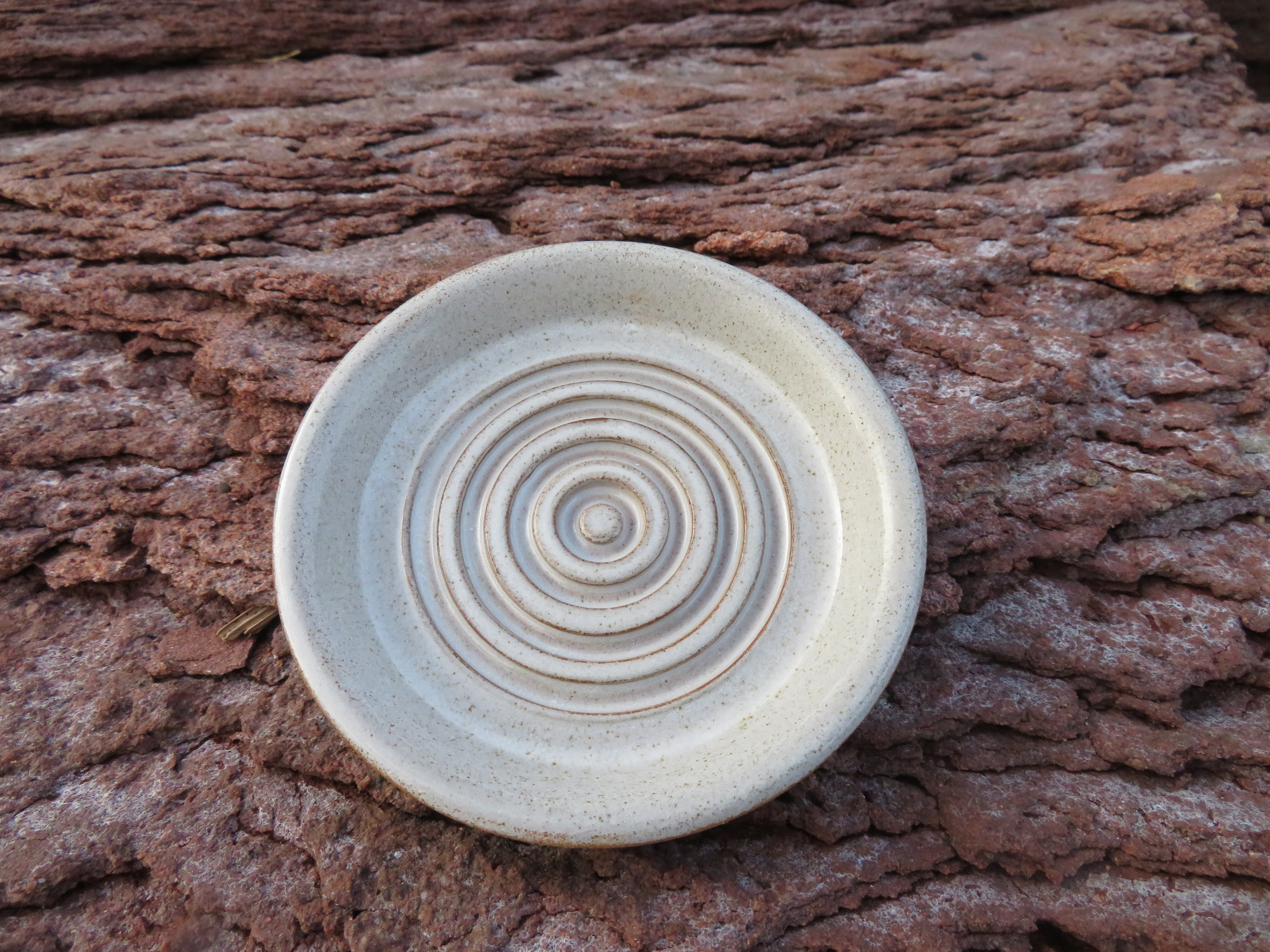 Ceramic disc with concentric circles on a textured brown surface