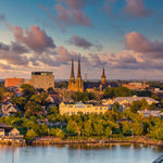 Cityscape with buildings and a cathedral near a body of water during sunset.