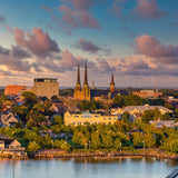 Cityscape with buildings and a cathedral near a body of water during sunset.
