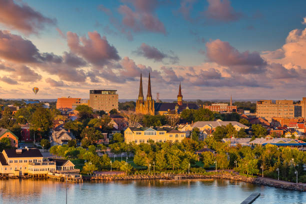 Cityscape with buildings and a cathedral near a body of water during sunset.