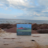 Island Potato Soap packaging on a piece of driftwood with a beach background