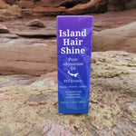 Island Hair Shine product packaging on a rocky surface