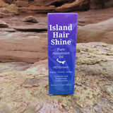 Island Hair Shine product packaging on a rocky surface