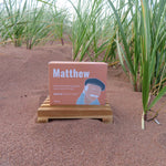 Book titled 'Matthew' on a stand in a field of tall green plants