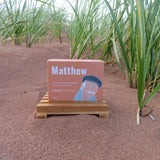 Book titled 'Matthew' on a stand in a field of tall green plants