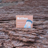 Soap packaging with a person's name on it placed on textured brown surface
