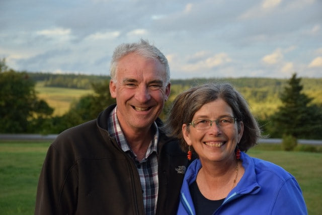 Two people smiling outdoors with a scenic background