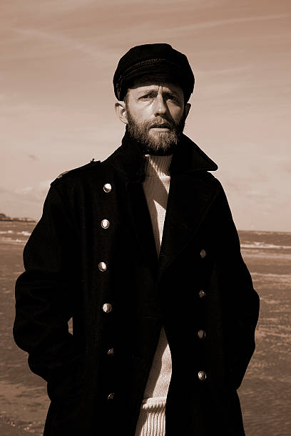 Man wearing a dark coat and hat in a sepia-toned landscape