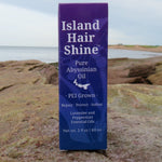 Island Hair Shine Pure Abyssinian Oil bottle on a rocky surface with a scenic background