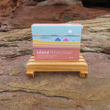 Box of Island Potato Soap on a wooden stand with a natural rock background