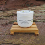 White jar of Island Potato Face & Hand Creme on a wooden stand with a natural rock background
